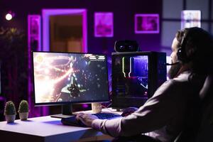 Streamer in studio streaming for online viewers, talking with them, creating content. Pro gamer broadcasting from dark living room, greeting fans watching him on online channel photo