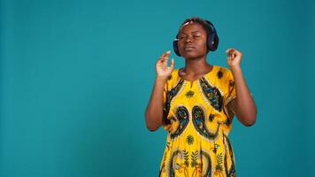 Carefree relaxed woman listening to music and dancing in the studio, having fun with a new groovy playlist. Happy optimistic person enjoys radio songs on her audio headset. Camera B. photo