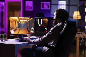 Man playing science fiction FPS videogame, having fun in dark cozy apartment room. Gaming enthusiast competing in PvP online multiplayer game, shooting other players with futuristic gun laser bullets photo