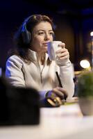 editor correcting faulty footage, grading and coloring, enjoying cup of coffee in creative studio. Videographer adding special effects to clips, drinking hot beverage in media company office photo
