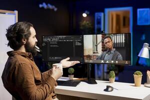 IT developer working from home in remote videocall with BIPOC coworker, testing programs and systems. Programmer checking code with colleague in internet videoconference meeting photo
