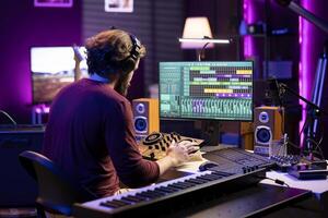 Skilled producer mixing and mastering sounds on stereo console, adjusting volume levels by twisting pre amp knobs in home studio. Audio engineer working with professional post production gear. photo