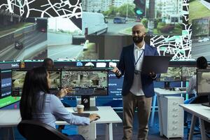 Middle eastern supervisor oversees order tracking activity in control center, ensuring express delivery service by using public surveillance system. Employees guiding the couriers around the city. photo