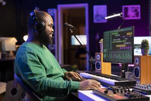 Music producer editing old audio recordings on professional software, operating on mixing console and stereo gear. Sound engineer producing new songs with acoustical tunes in home studio. photo