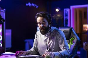 Pro gamer at home talking with teammates using headphones mic, competing together in intense multiplayer videogame. Person having gaming session with friends, communicating online photo