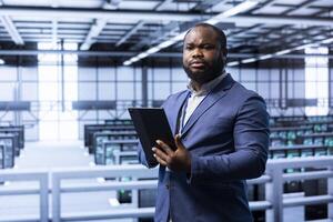 System administrator in server room establishment installing newly ordered storage units using tablet. Software developer working in data center facility housing storage rackmounts photo