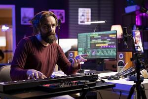 Young talented instructor hosting piano lessons on social media channel, teaching people to play music on midi controller synthesizer. Musical producer explains playing on electronic keyboard. photo