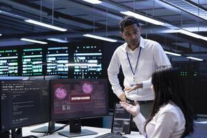 Programmers doing teamwork in server hub trying to protect hardware from hacker stealing information. Colleagues in data center workspace trying to fix security breach alert caused by virus photo