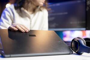 Technician doing software debugging using laptop, checking errors in lines of code displayed on computer monitors. Woman working from home fixing coding mistakes using notebook device photo