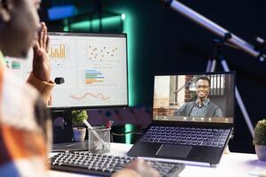 African american male freelancer attends virtual meeting call with clients on laptop, working at home and sharing insight on income statistics. Person looking at screen and listening to call. photo