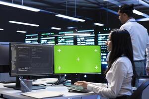 Team of technicians using green screen laptop to do maintenance on high bandwidth, dedicated game servers used to accommodate incoming traffic of online users joining from worldwide locations photo