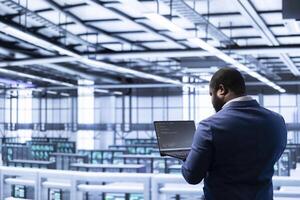 Admin in data center identifying and solving technical malfunctions related to data center systems. IT employee managing, maintaining and securing server hub and mainframe rigs inside photo