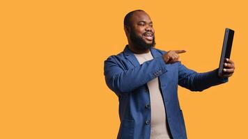 African american man having funny conversation with friends during teleconference meeting using tablet, studio background. Person laughing, having fun with mates during internet videocall, camera B photo