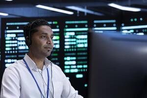Developer using computer to troubleshoot hardware and software errors in server farm. Man in high tech facility implementing and maintaining server and network infrastructure in data center photo