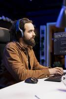 Programmer listening music and writing lines of code filtering malicious traffic from cybercriminals attempting to steal company data. IT professional wearing headphones while preventing malware photo