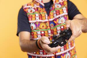 Close up shot of gamer holding controller, focused on finishing videogame level, pressing buttons. Man gaming with gamepad, solving quests, isolated over yellow studio backdrop photo