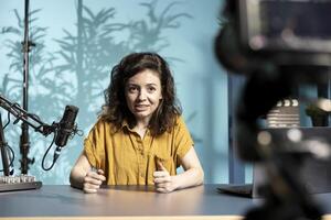 Content creator talking about herself while recording with production gear in studio interior. Entertainer talking in professional microphone, starting vlog, filming with high quality camera photo