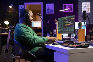 Sound designer playing piano and recording audio files on DAW software, producing new tracks and adding effects in post production. Artist musician creating songs for music industry. photo