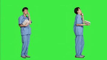 Medical assistant talking to patients on landline phone call in studio, using office retro telephone with cord against greenscreen. Nurse answering hospital line to make appointments. Camera A. photo