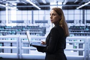 Data center computer scientist ensuring safety and security of database using notebook. Cybersecurity specialist in server farm preventing unauthorized access posing risks for business photo
