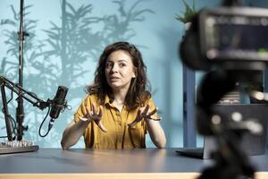 ASMR creator with high tech mic and specialized filming gear does anti stress in cozy home studio. Woman using professional microphone and camera to do relaxing content for subscribers photo