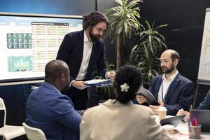 Project leader joins in a conference room with his management team to go over details on legislative shifts that might influence their duties. Director highlighting reports with collected data. photo