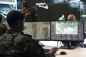 Army IT specialist interprets registered satellite CCTV footage for insight while he is targeting enemy positions. Air force crew officer takes notes about hostile vessels trajectory, reconnaissance. photo