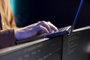 Programmer typing on laptop to fix vulnerabilities in software enabling attackers to compromise systems. Man taking care of security exposures in operating system, writing code on notebook, close up photo