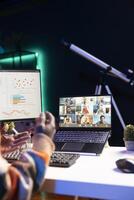 Waving from his apartment, black man using laptop to participate in online meetings. Male freelancer uses wireless technology for conferencing with colleagues to discuss work remotely. photo