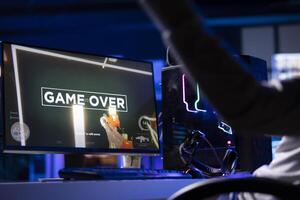 Gamer throwing headphones in frustration after receiving game over screen in first person shooter. Player upset after being defeated in videogame, losing all health, failing to win level photo