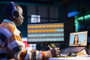 Black man photo editor in a well organized workspace editing images on dual monitors using advanced software tools, displaying creativity and professional dedication. Computer setup.