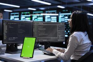 Computer scientists in data center checking equipment performance on green screen tablet after upgrading machines. Admins doing maintenance on rigs in servers room using chroma key device photo