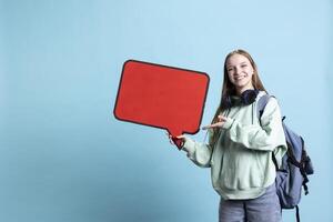 Smiling woman holding red speech bubble sign of empty copy space for message. Joyous teenager presenting thought bubble cardboard used as promotion concept, isolated over studio background photo