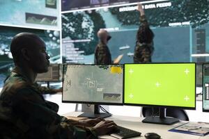 Serviceman uses green screen and satellite CCTV imagery in army power base, working on reconnaissance defense program. Trooper monitoring real time data with gps tracking footage. photo
