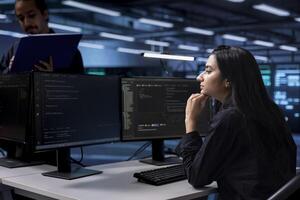 Software developer reconfiguring server farm to optimize it for data processing requirements of customers. Indian woman ensuring data center equipment operates efficiently photo