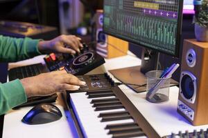 Music producer twisting pre amp knobs on mixing console, editing his audio recordings in home studio. Skilled composer producing new soundtracks with modern equipment. Close up. photo