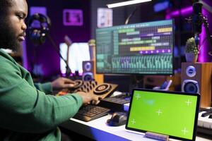 Producer composer mixing and mastering his songs with stereo tools, copyspace screen on a tablet. Audio technician improving sound quality on tracks recorded in post production. photo