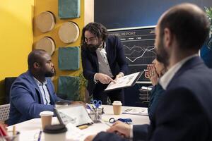 Staff members from a business enterprise discussing insight and details for a new project during a corporate conference. Company employees are getting informed about marketing developments. photo