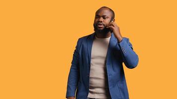 African american man having important phone call with business partner using smartphone, studio background. BIPOC person walking around discussing company matters during telephone call, camera B photo