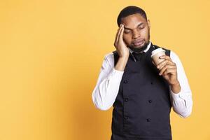 Restaurant employee dealing with a painful headache while he serves clients, carrying a cruet set for excellent customer satisfaction. Unwell waiter working in pain with migraine. photo