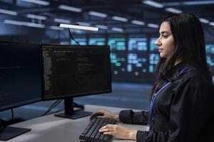 Software programmer in server farm tasked to oversee mainframes devices used for managing databases. Indian woman in data center establishment doing checkup on rackmounts storing information photo