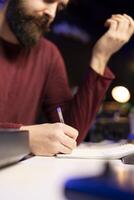 In his home studio, the musician writes down lines and melodic elements to create new soundtracks. Using digital audio workstation, recordings song and applies sound effects in post production. photo