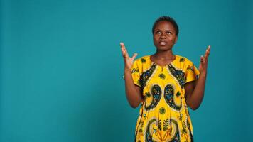 Young positive woman praying to God for health and happiness, saying a prayer and being hopeful in studio. Cheerful optimistic girl asking for good vibes and fortune, native ethnic attire. Camera B. photo