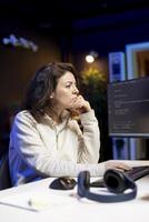 Freelancer doing software debugging using computer, checking errors in lines of code displayed on PC monitors. IT professional in apartment fixing coding issues using desktop PC photo