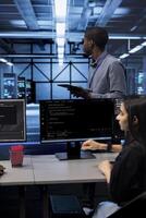 Engineer in data center updating systems to keeps performance up and protect servers from easily exploitable software vulnerabilities. Employee looking for errors causing servers to slow down photo