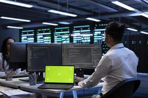 Teamworking programmers in data center using isolated screen laptop to find firewall misconfigurations affecting servers. Workers in server room checking systems bottlenecks using mockup notebook photo