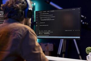 Computer scientist listening music while securing company servers from virus attacks. IT remote employee at home wearing headphones and building firewalls protecting data photo