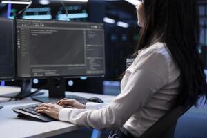 Close up shot of software developer in data center typing on keyboard, working on computer to do checkup on hardware. Woman inputting data on PC in server hub after finishing maintenance photo