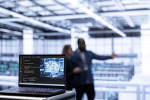 Focus on AI software on laptop in front of team of admins programming in AI data center. Close up of notebook in high tech server hub workspace used by workers upgrading artificial intelligence system photo