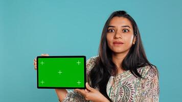 Energetic salesman doing influencer marketing using green screen tablet, studio background. Lively woman reviewing product, holding empty copy space mockup digital device, camera B photo